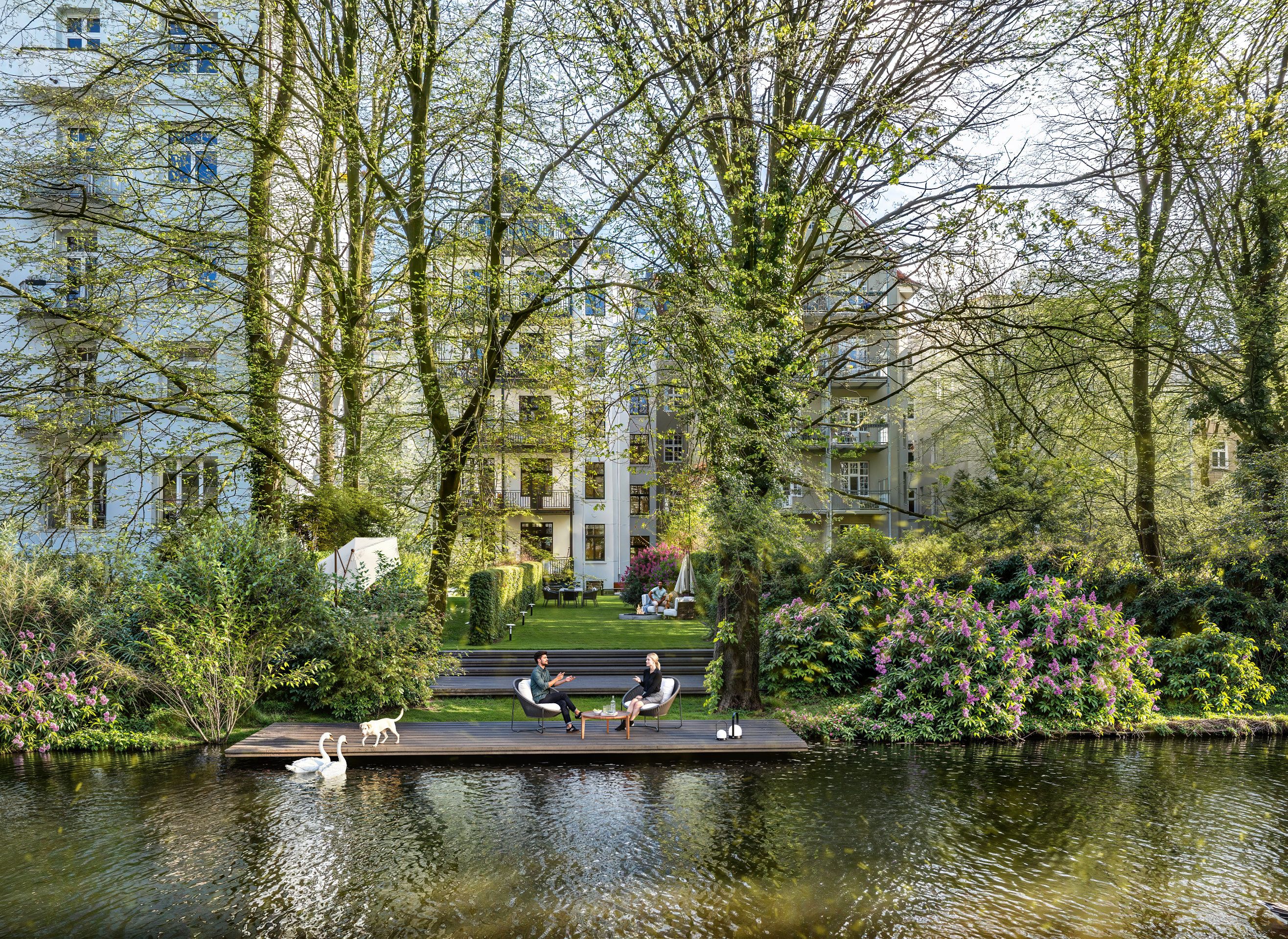 Fotorealistische 3D-Visualisierung des ruhigen Hintergartens im Andreasstraße-Projekt, mit Sitzbereich am Wasser, üppigem Grün und Schwänen. Fotorealistische 3D-Visualisierung des ruhigen Hintergartens im Andreasstraße-Projekt, mit Sitzbereich am Wasser, üppigem Grün und Schwänen.